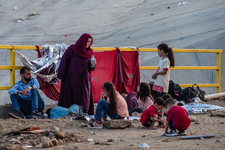 عائلة تقع بين الجدران الحدودية الأولية والثانوية للمكسيك والولايات المتحدة تنتظر أن تتم معالجتها من قبل إدارة الهجرة الأمريكية في سان يسيدرو في 12 سبتمبر 2023.